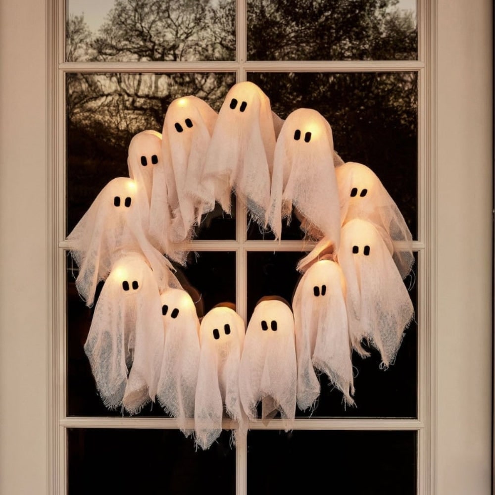 Coroa de fantasmas de Halloween com doze figuras LED luminosas expostas sobre um fundo de gaze preta