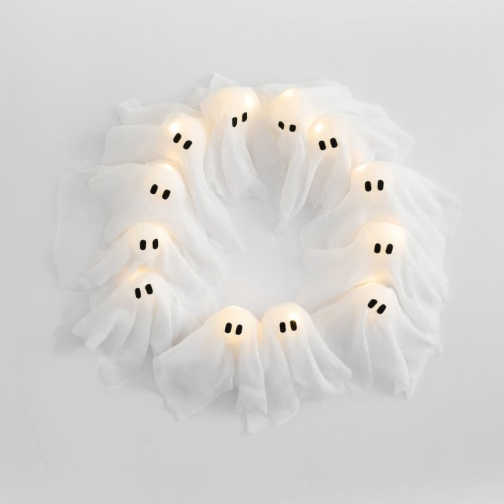 Coroa de fantasmas de Halloween com doze figuras LED luminosas expostas sobre um fundo de gaze preta