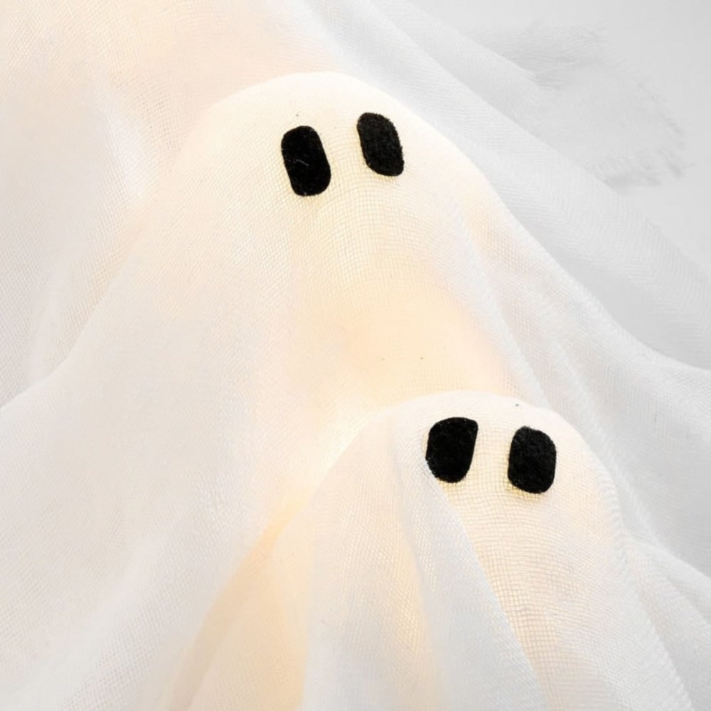 Coroa de fantasmas de Halloween com doze figuras LED luminosas expostas sobre um fundo de gaze preta