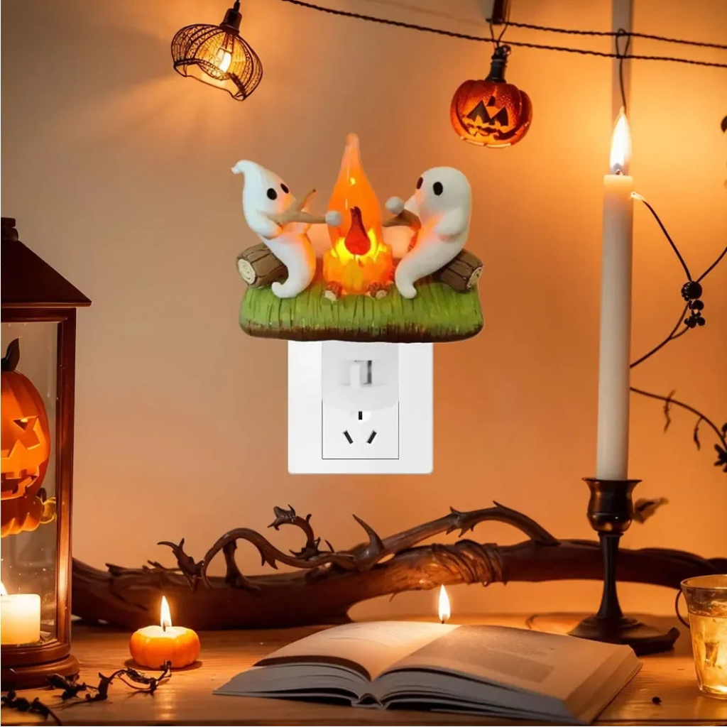 Wtykowa lampka nocna LED z duchem przy ognisku na Halloween - scena z pieczeniem pianki marshmallow